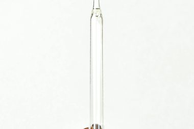 Minimalist image of a glass dropper in an amber bottle, perfect for beauty or science themes.