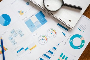 A set of financial charts and graphs with a magnifying glass, perfect for business reports.